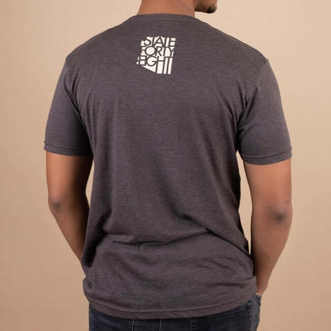 Back view of a man wearing a State Forty Eight t-shirt showcasing the logo design in white on a gray background.