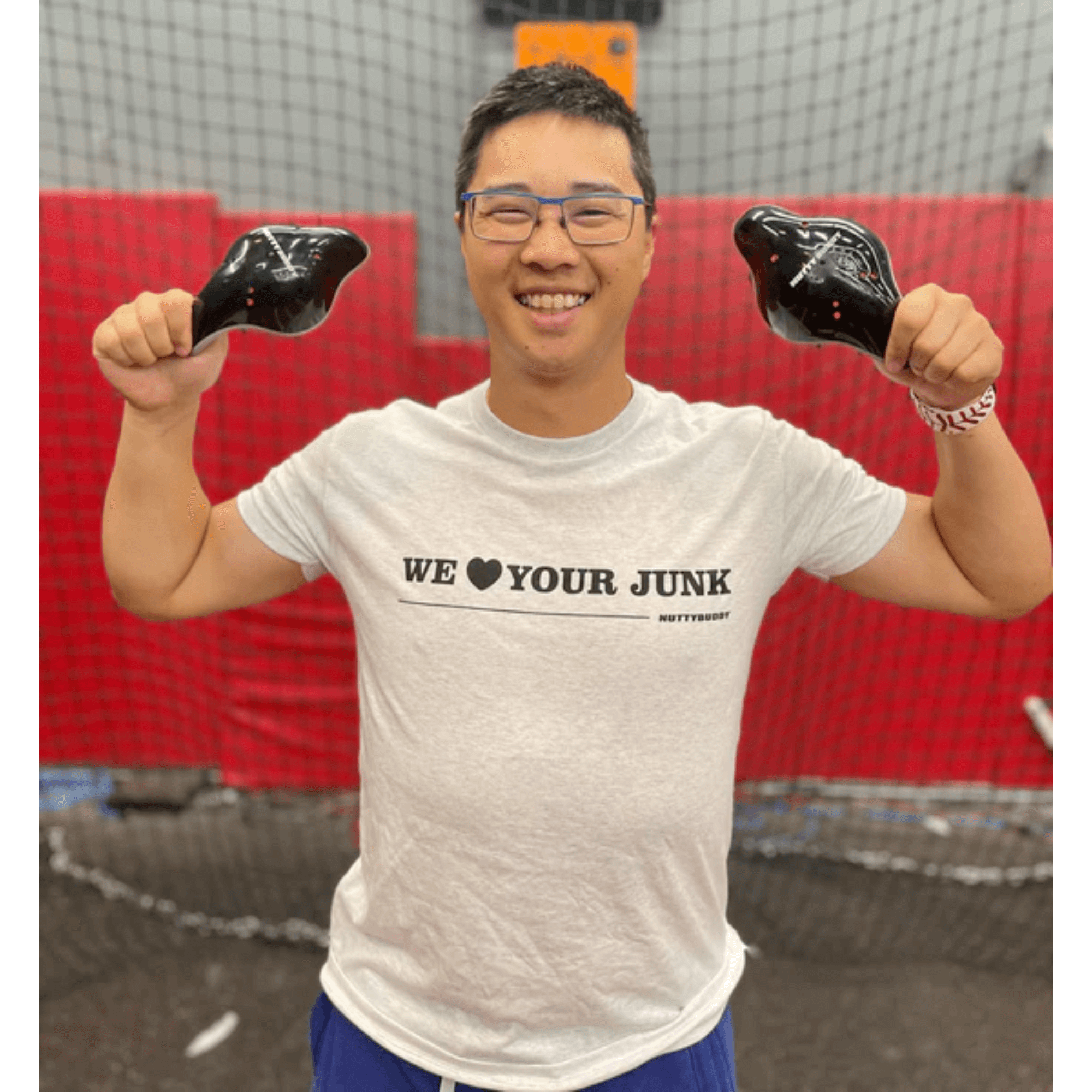 Man wearing NuttyBuddy "We ❤ Your Junk" athletic fit shirt, holding weights in a gym setting.