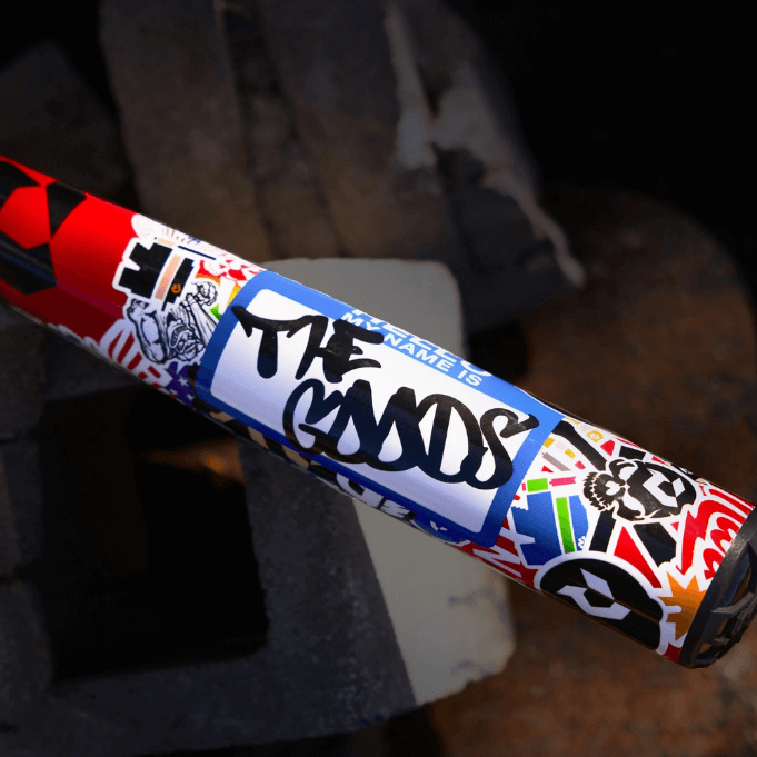 2026 DeMarini The Goods Sticker Bomb BBCOR Baseball Bat, featuring bold graphics and a hybrid design for powerful swings.