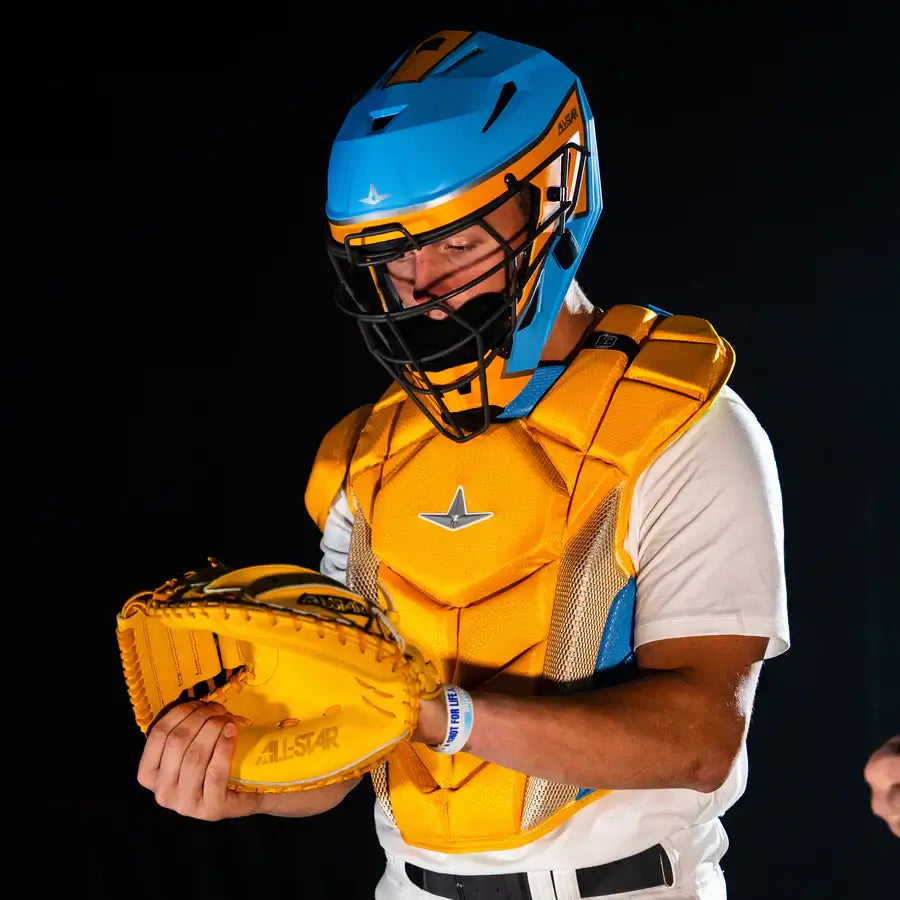 Person wearing All-Star MVP-Pro Short Fuse Catcher's Kit Boston Limited Edition Sky Blue/Yellow, holding catcher's mitt.