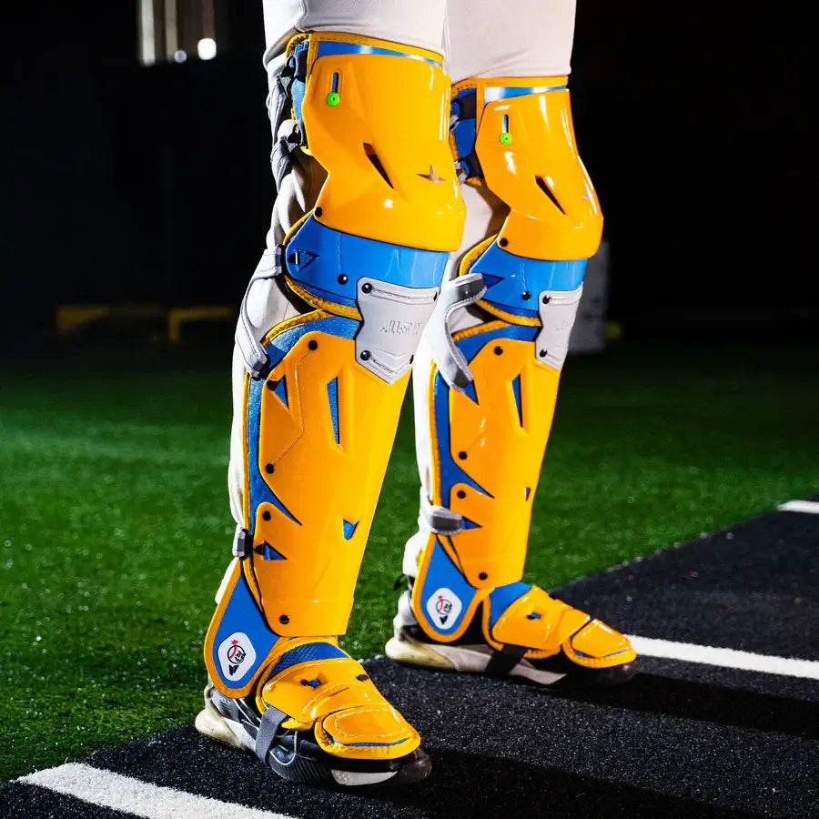 Side view of All-Star MVP-Pro Short Fuse Catcher's Kit leg guards, Boston Limited Edition, Sky Blue/Yellow, showing vibrant design.