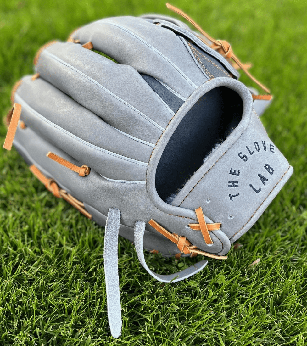 The Glove Lab 12" grey and navy utility glove with tan laces and embroidery, displayed on green grass.